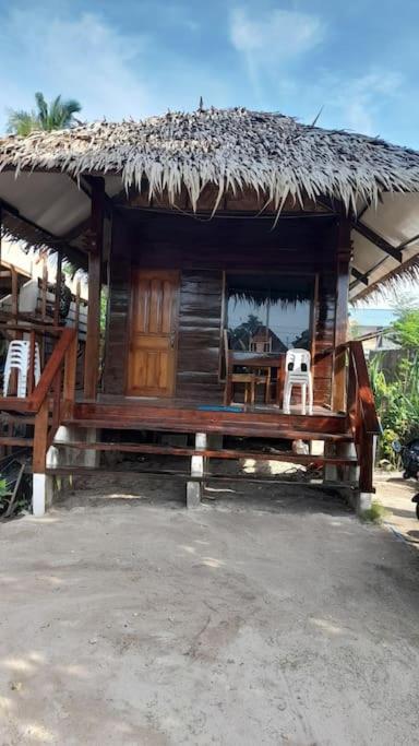 a small house with a straw roof and a chair at Panawan Cinco in General Luna