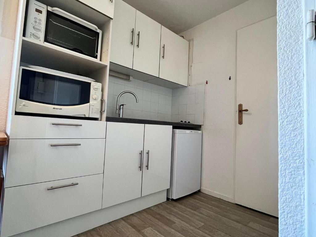 eine Küche mit weißen Schränken, einer Mikrowelle und einem Kühlschrank in der Unterkunft Appartement Villard-de-Lans, 2 pièces, 4 personnes - FR-1-515-164 in Villard-de-Lans