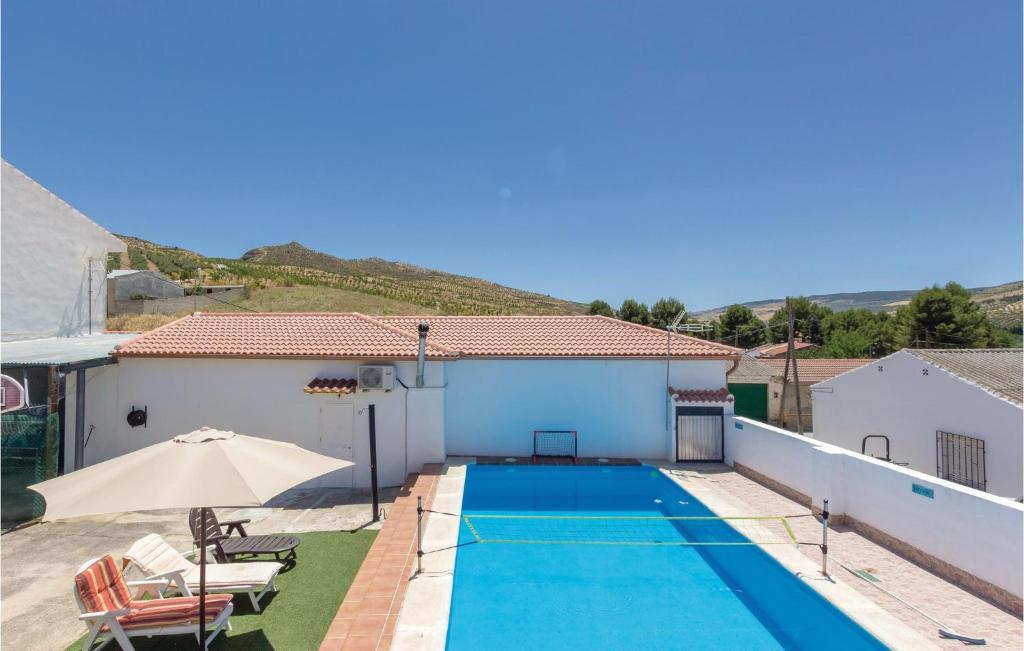 a swimming pool with an umbrella and a house at Beautiful Home In Cacn granada With 2 Bedrooms, Wifi And Outdoor Swimming Pool in Cacin