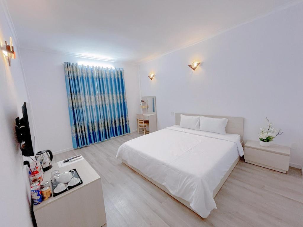 - une chambre blanche avec un lit blanc et une fenêtre dans l'établissement Sài Gòn - Hà Tiên, à Hà Tiên