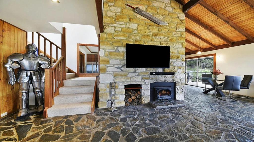 a living room with a stone fireplace and a statue at Sydney View - Stay 3 Pay 2 in Woodford