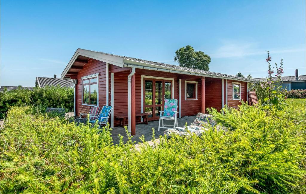 ein kleines rotes Haus mit zwei Stühlen auf einer Veranda in der Unterkunft 2 Bedroom Lovely Home In Faaborg in Bøjden