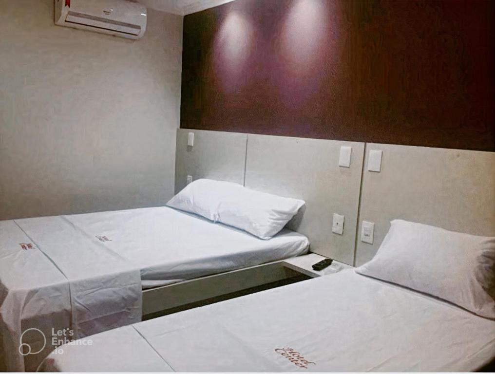 two beds in a small room with white sheets at Hotel Center in Feira de Santana