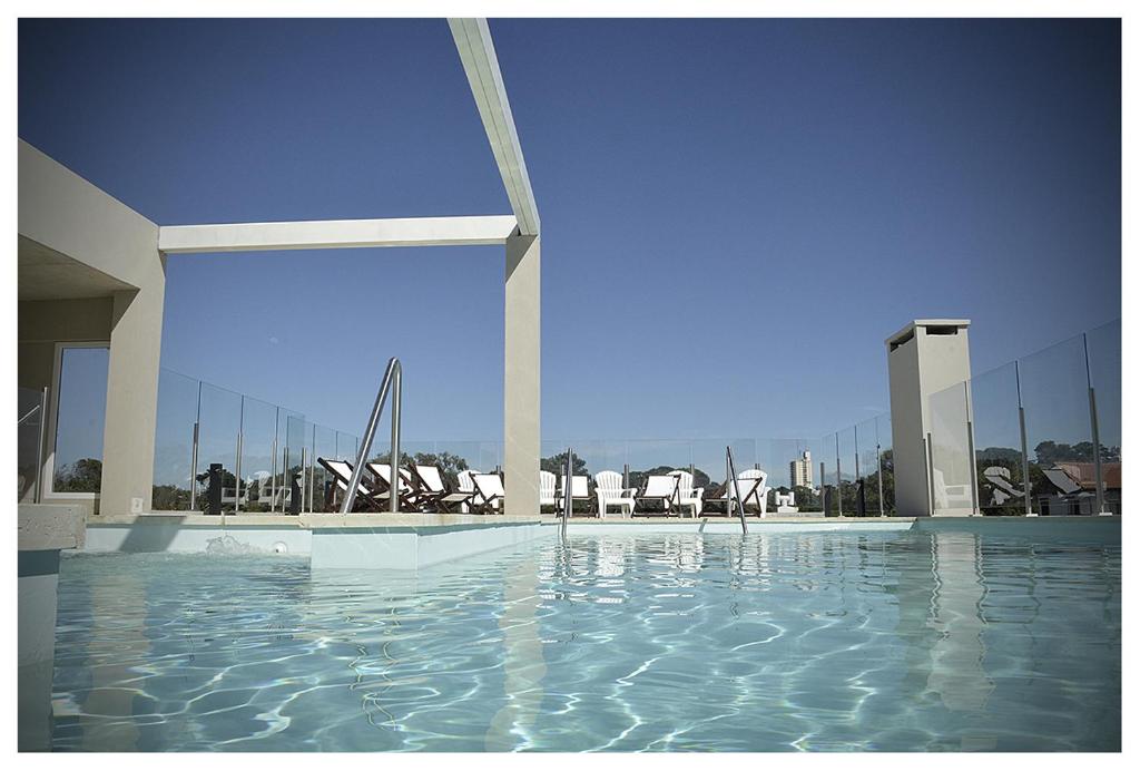 una piscina con sillas y agua en un edificio en Amura Suites en Pinamar