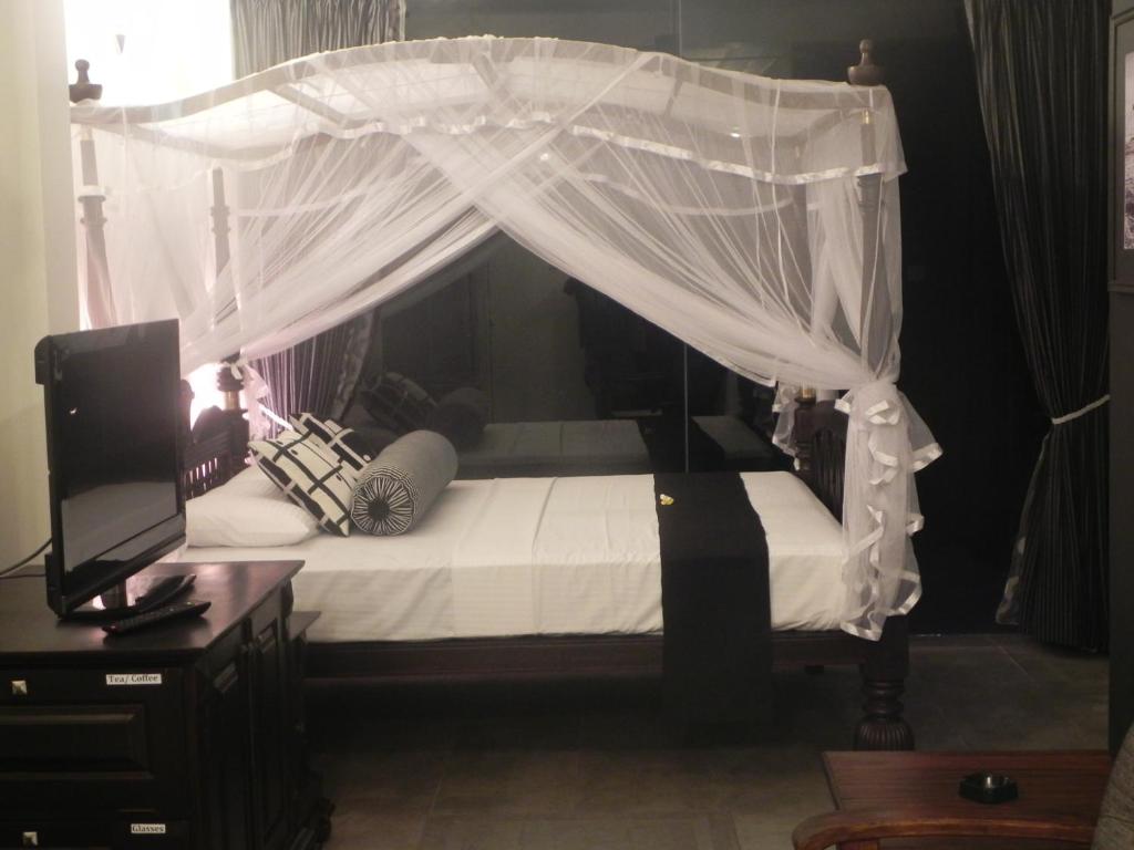 a bedroom with a canopy bed with white curtains at Amanda Beach Villas in Unawatuna