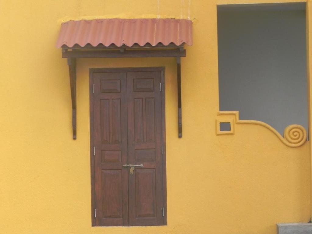a door on the side of a yellow building with a pink roof at Amanda Beach Villas in Unawatuna