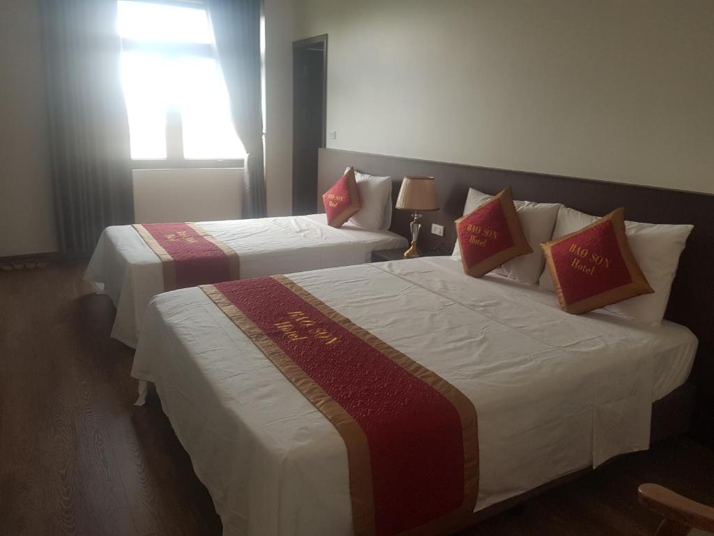 two beds in a hotel room with a window at Khách sạn Bảo Sơn Bắc Giang in Làng Thành