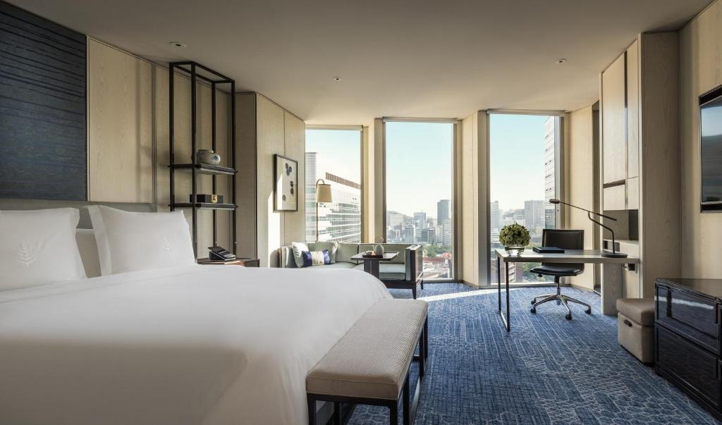 a hotel room with a bed and a desk and windows at Four Seasons Hotel Seoul in Seoul