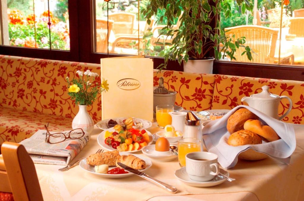 a table with a breakfast of bread and fruit and orange juice at Thermenwelt Hotel Pulverer in Bad Kleinkirchheim