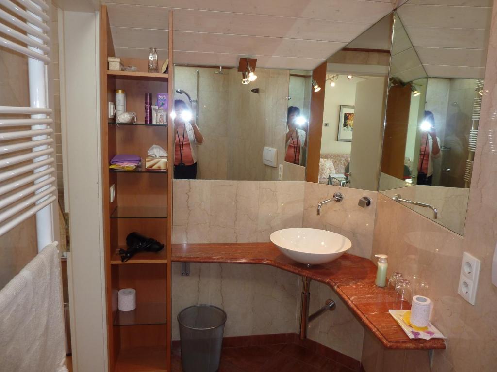 dwie osoby robiące zdjęcia łazienki z umywalką w obiekcie Apartment Leonardo w mieście Bolzano