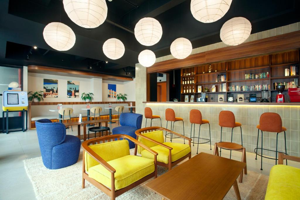 a restaurant with colorful chairs and a bar at Liberta Hub Blok M Jakarta in Jakarta