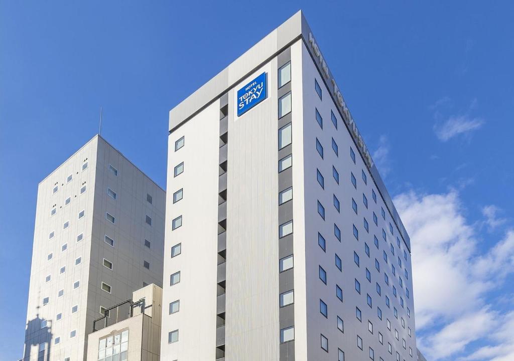 a tall white building with a blue sign on it at Tokyu Stay Sapporo Odori in Sapporo