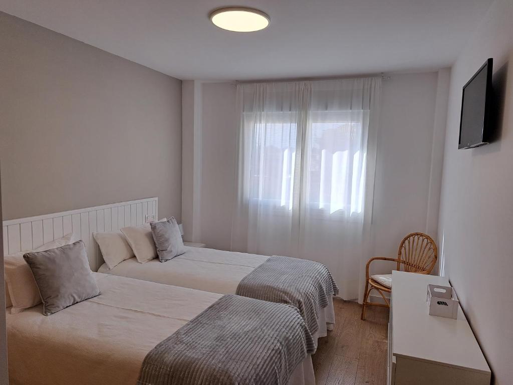 a hotel room with two beds and a window at Apartamento Calvarios in Sanxenxo