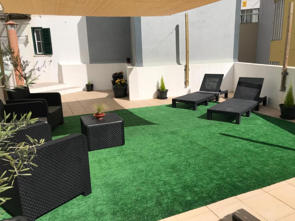 a patio with green artificial grass and chairs at MariaHouse in Faro