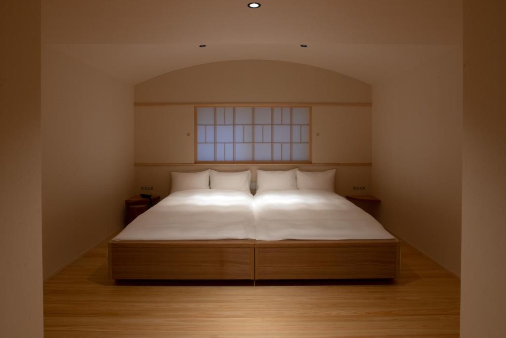 a bedroom with a bed with white sheets and a window at Tsukihitei in Nara