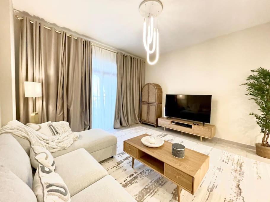 a living room with a couch and a tv at Dar Vacation - Modern Luxury 1BR Apartment in MJL in Dubai