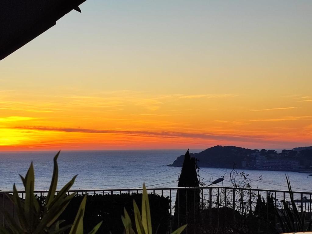 un coucher de soleil sur l'océan avec une clôture dans l'établissement T2 vue mer, à Six-Fours-les-Plages