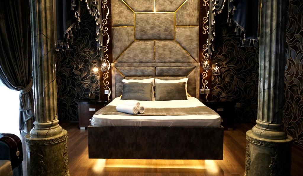 Schlafzimmer mit einem Bett mit einem großen Kopfteil in der Unterkunft Egoist luxury Hotel in Baku