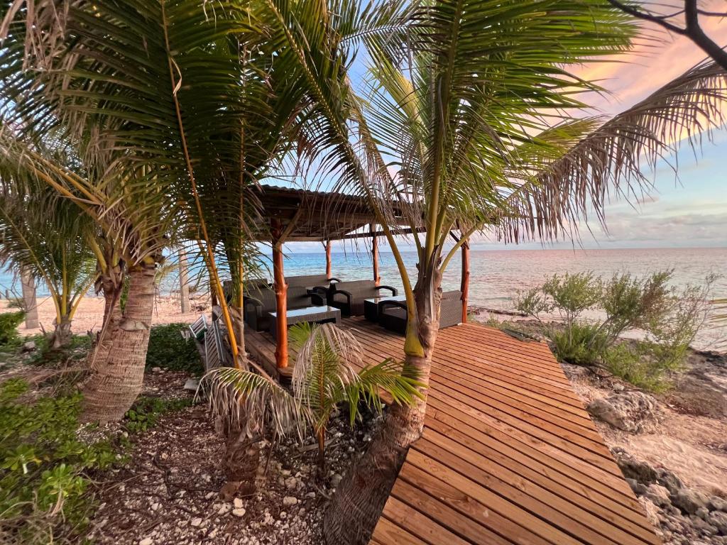 un chemin en bois menant à une maison sur la plage dans l'établissement Te Mao, à Avatoru