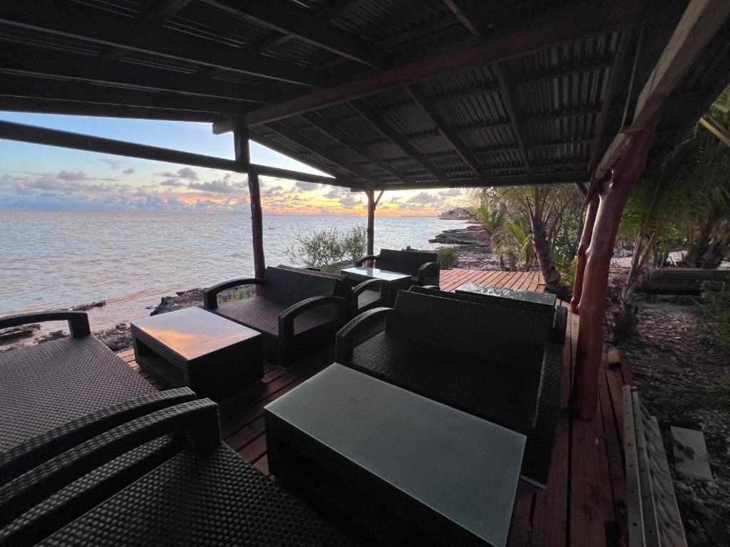 a deck with chairs and tables on the water at Te Mao in Avatoru