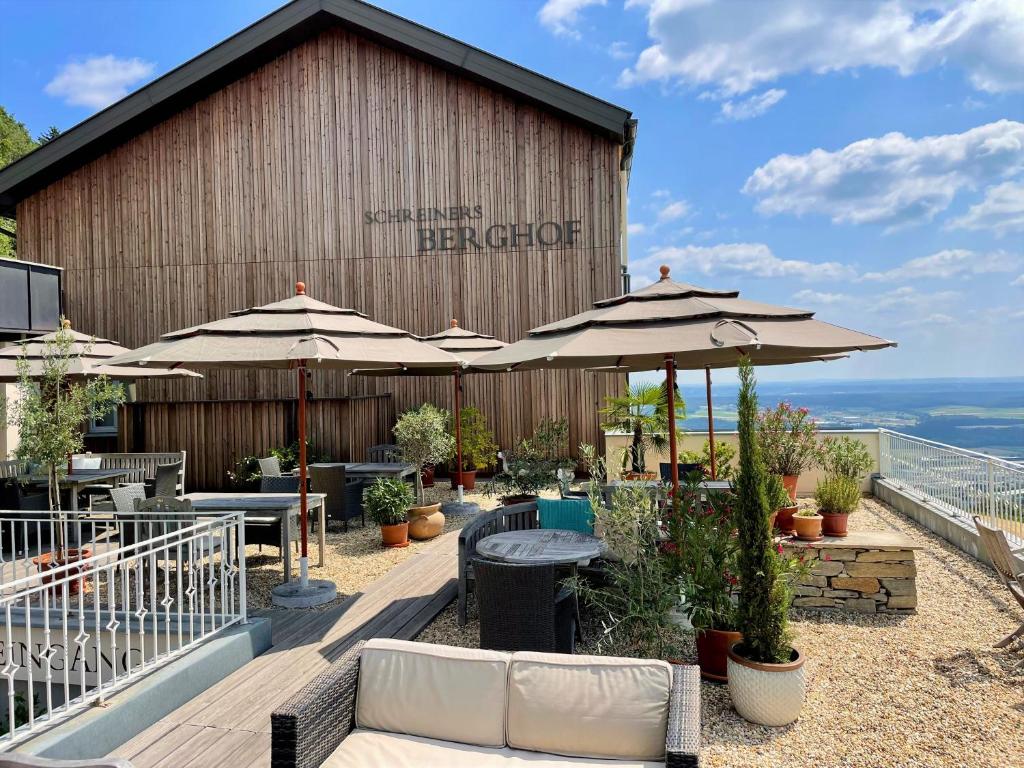 eine Terrasse mit Tischen und Sonnenschirmen vor einem Gebäude in der Unterkunft Schreiners Berghof in Hartberg