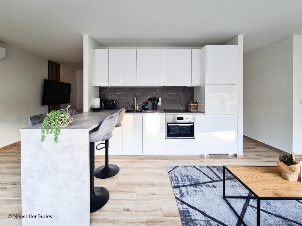 a kitchen with white cabinets and a table at St. Antoni Suite 2 in Eisenstadt