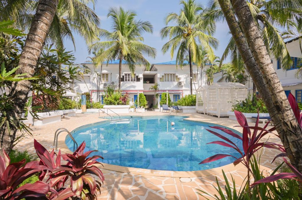 a swimming pool in front of a house with palm trees at Soul Vacation Resort and Spa,Colva in Colva