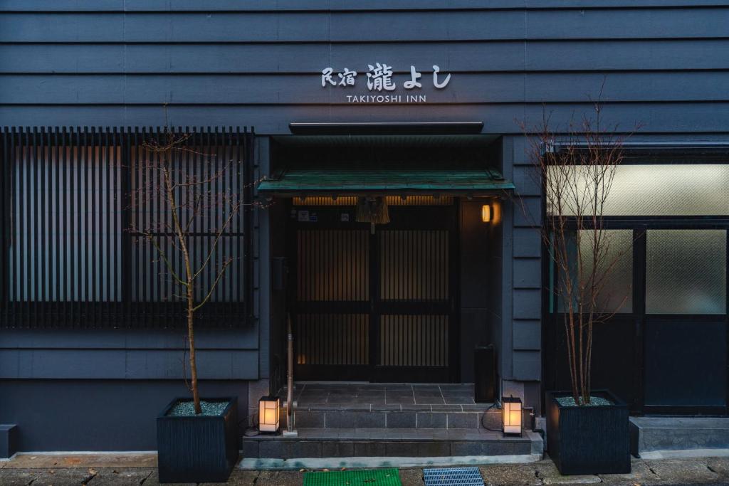 een voordeur van een restaurant met twee potbomen bij Guest House Takiyoshi in Hongu