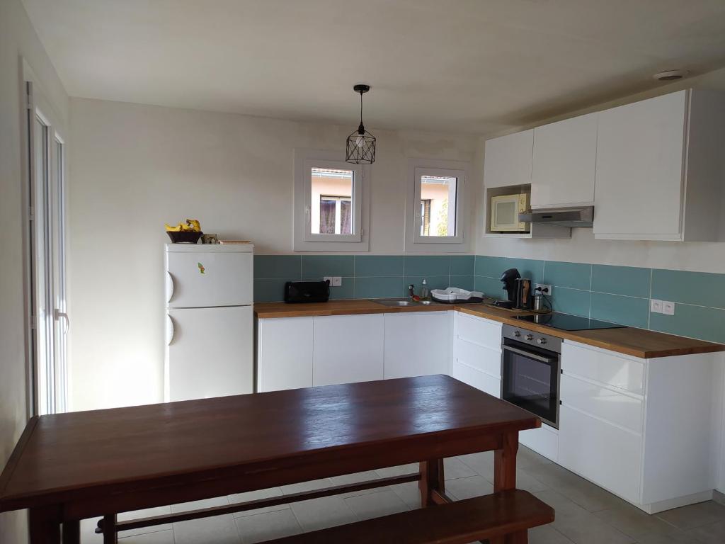 a kitchen with white cabinets and a wooden table at Maison bien située et au calme in Gap