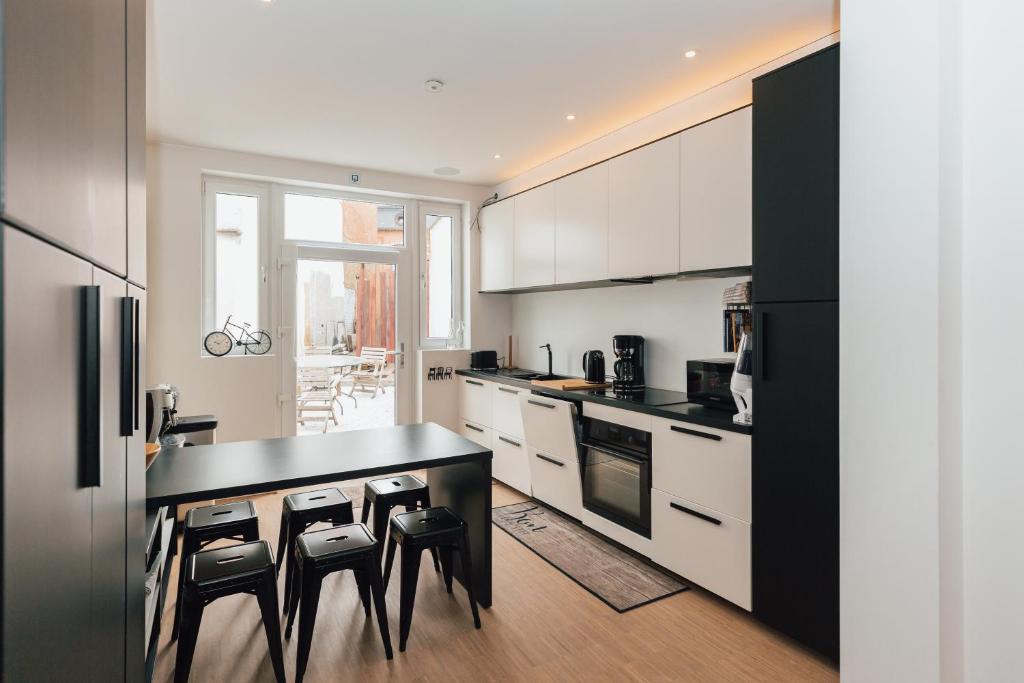a kitchen with white cabinets and a black counter top at Vakantiehuis Vélolit in Oudenaarde