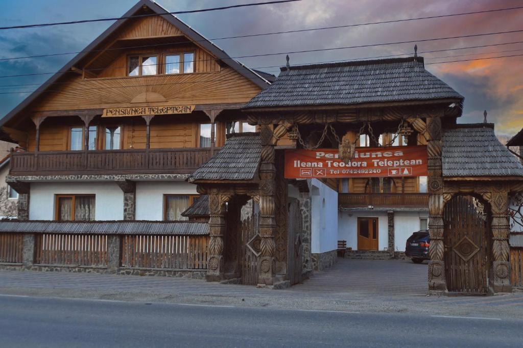 ein großes Holzhaus mit einem Tor davor in der Unterkunft Pensiunea Teodora Teleptean in Vadu Izei