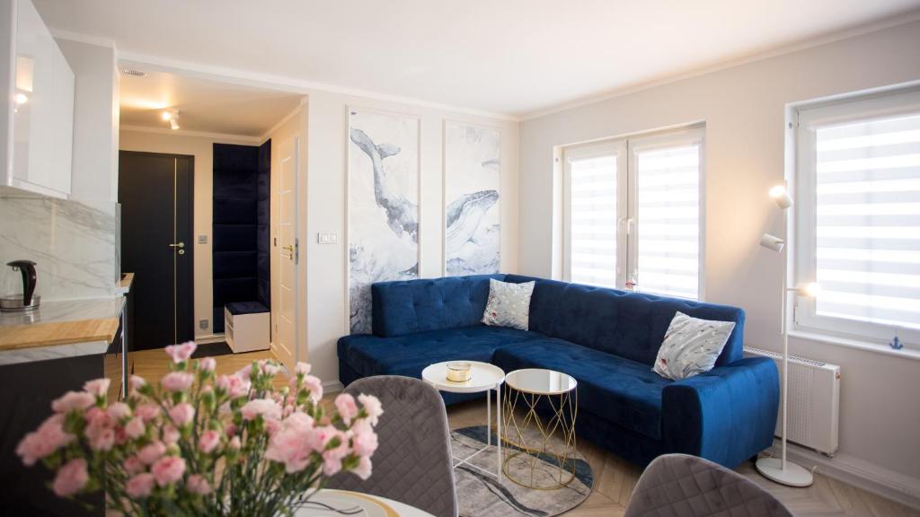 a living room with a blue couch and a table at Apartamenty Sun & Snow Stare Miasto Ustka in Ustka