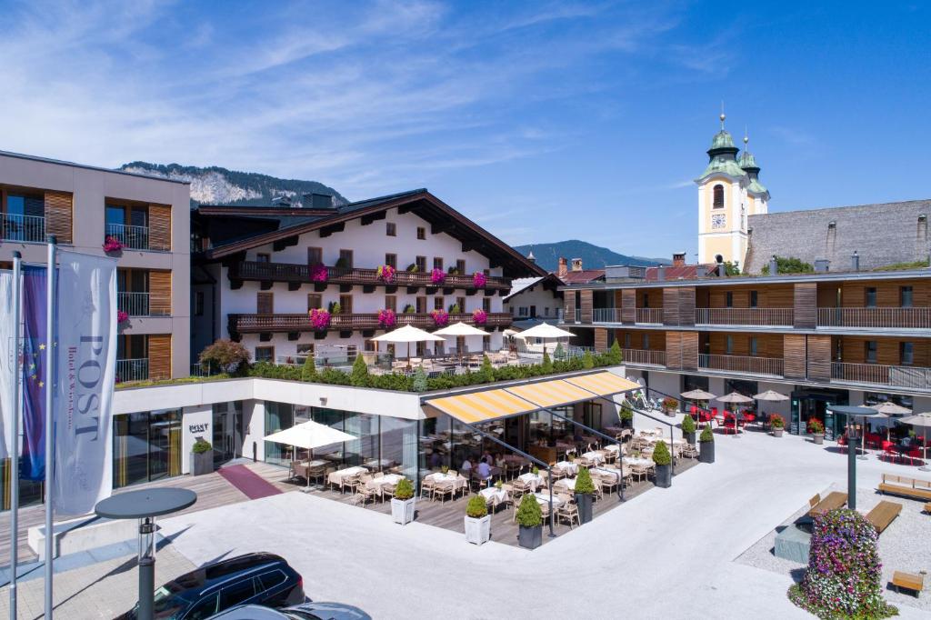 un edificio con cortile attrezzato con tavoli e sedie di Hotel Wirtshaus Post a Sankt Johann in Tirol