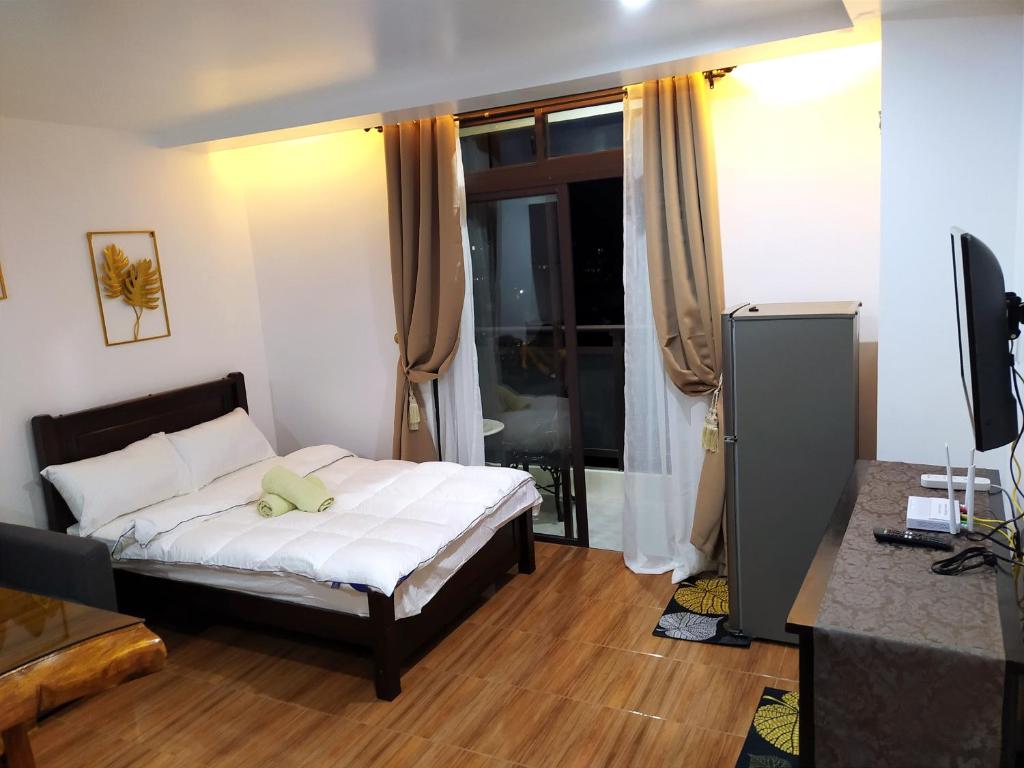 Schlafzimmer mit einem Bett mit weißer Bettwäsche und einem TV in der Unterkunft UNIT 3F-18 MEGATOWER RESIDENCES III in Baguio City