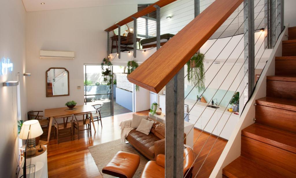 een woonkamer met een trap en een eetkamer bij Bondi Beach Loft by Sydney Dreams in Sydney