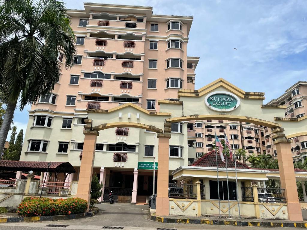 a large pink building with a clock on it at KUHARA COURT APARTMENT SUITE in Tawau