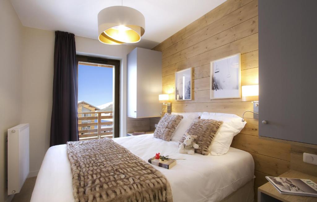 a bedroom with a large white bed with a window at Résidence Prestige Odalys l'Éclose in L'Alpe-d'Huez
