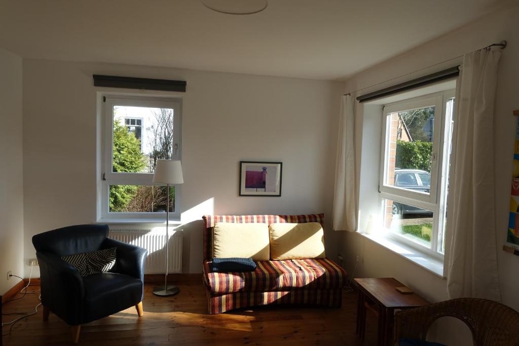 a living room with a couch and two windows at Ferienwohnung im Kieler Süden in Kiel