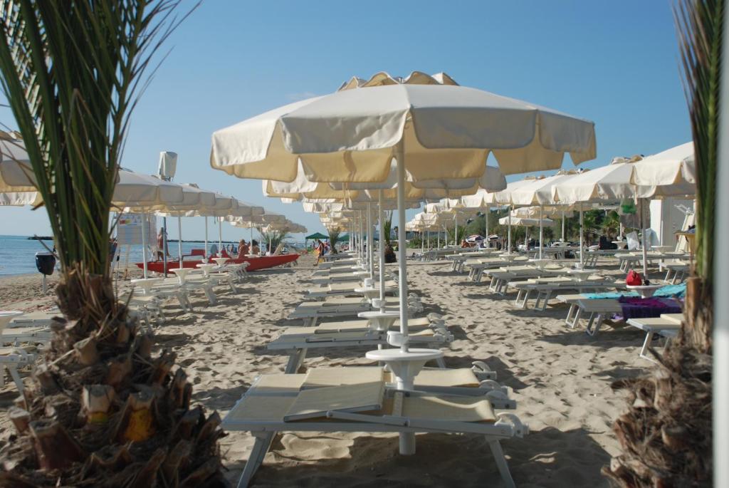 a beach with rows of chairs and umbrellas at Family Village Fontana Marina in Campofilone