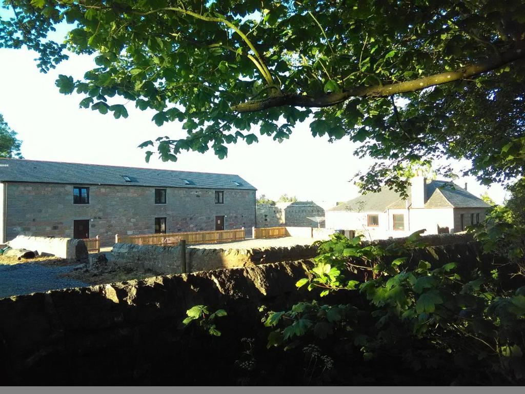 a view of a building from behind a tree at Berryhill West Steading - Sleeps 5 - Dog Friendly - Peterhead 1 mile - EV Point - Golf Driving Range - Rural Location in Peterhead