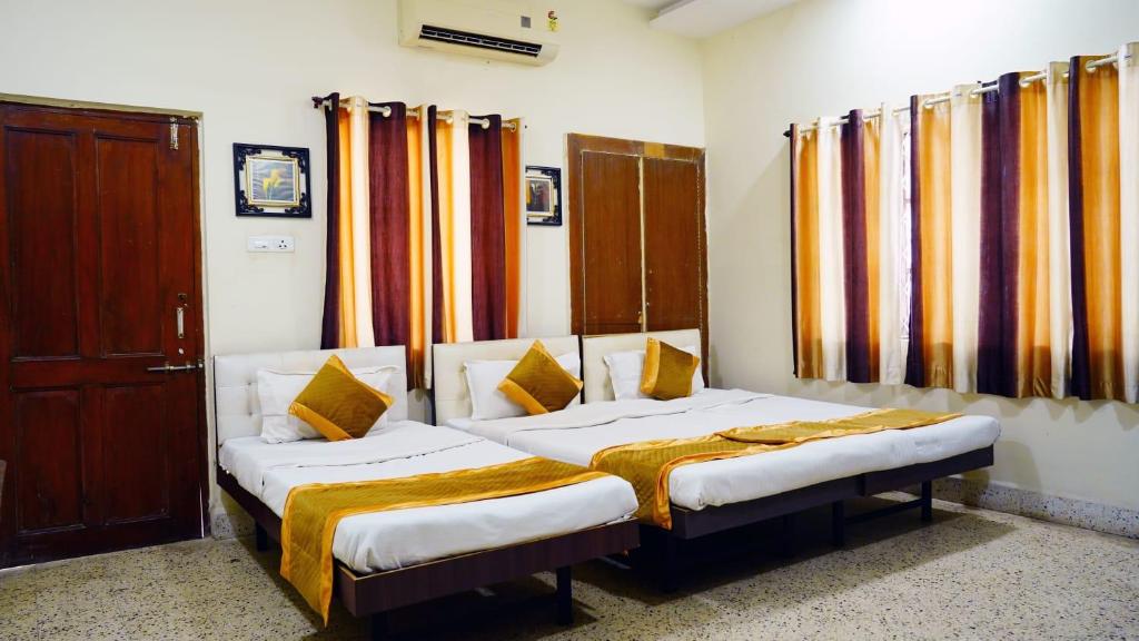 2 Einzelbetten in einem Zimmer mit Vorhängen in der Unterkunft Rampriya Service Apartment in Nagpur