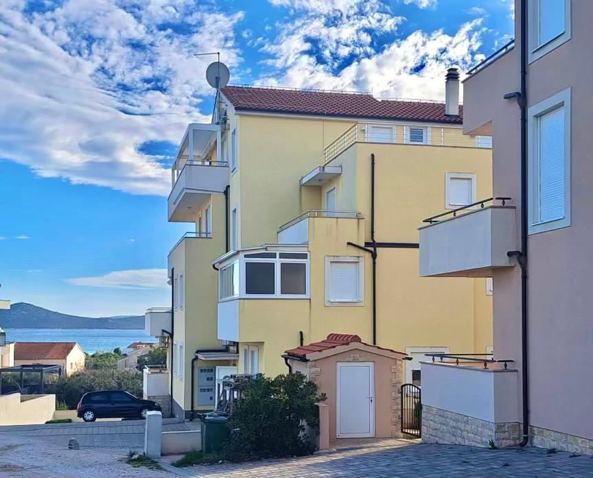 un immeuble jaune avec une voiture garée à côté dans l'établissement Apartman M&B, à Vodice