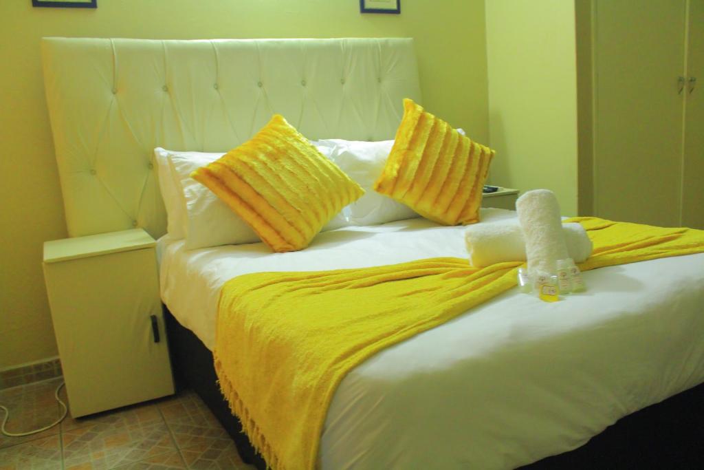 - un lit avec des oreillers jaunes et un animal rembourré dans l'établissement Butterflytree Guest House, à Phalaborwa