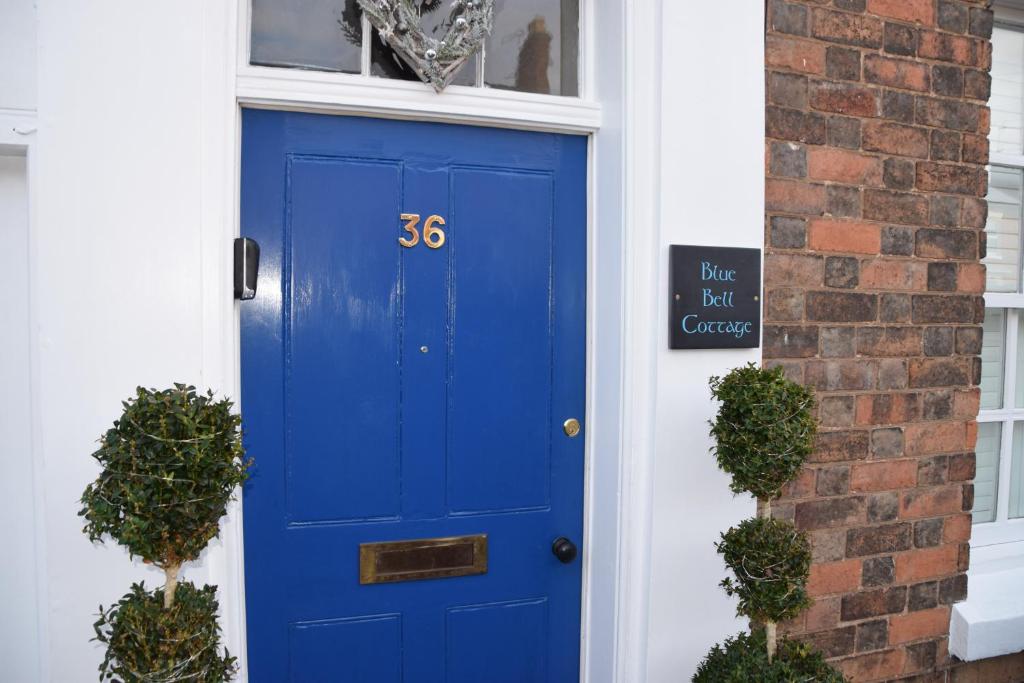 a blue door on a house with a sign on it at Bluebell Cottage , 36 Main Street in Alveston