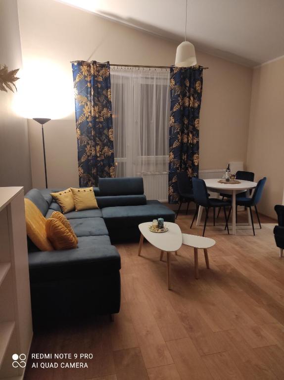 a living room with a blue couch and a table at Dawna Mleczarnia Apartament FAMILIJNY in Nowa Ruda