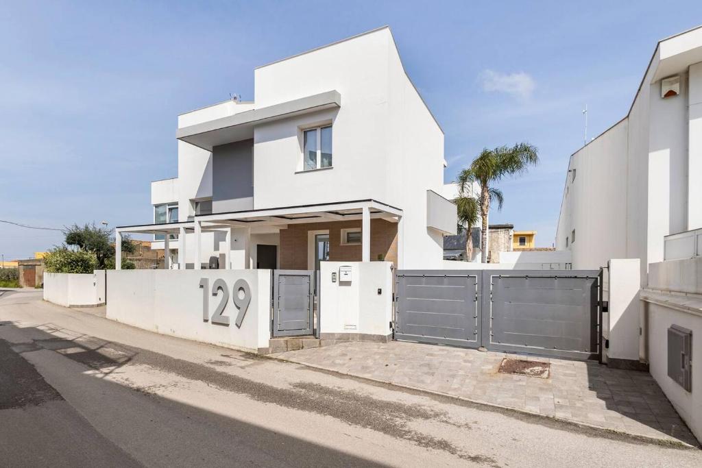 ein weißes Haus mit einem Tor auf einer Straße in der Unterkunft Villa Vanessa Milazzo, Sicily - EV Charge Station in Milazzo