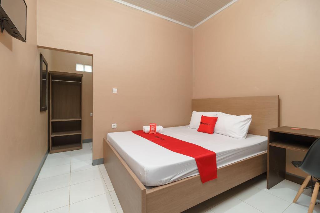 a bedroom with a bed with a red blanket on it at RedDoorz Syariah @ Bulak Kapal in Bekasi