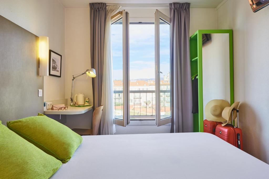 a bedroom with a bed and a desk and a window at Campanile Hotel Nice Centre Acropolis in Nice