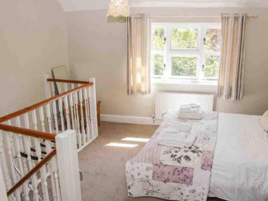 a small bedroom with a bed and a staircase at Charming 1-Bed Cottage located in Ironbridge in Ironbridge