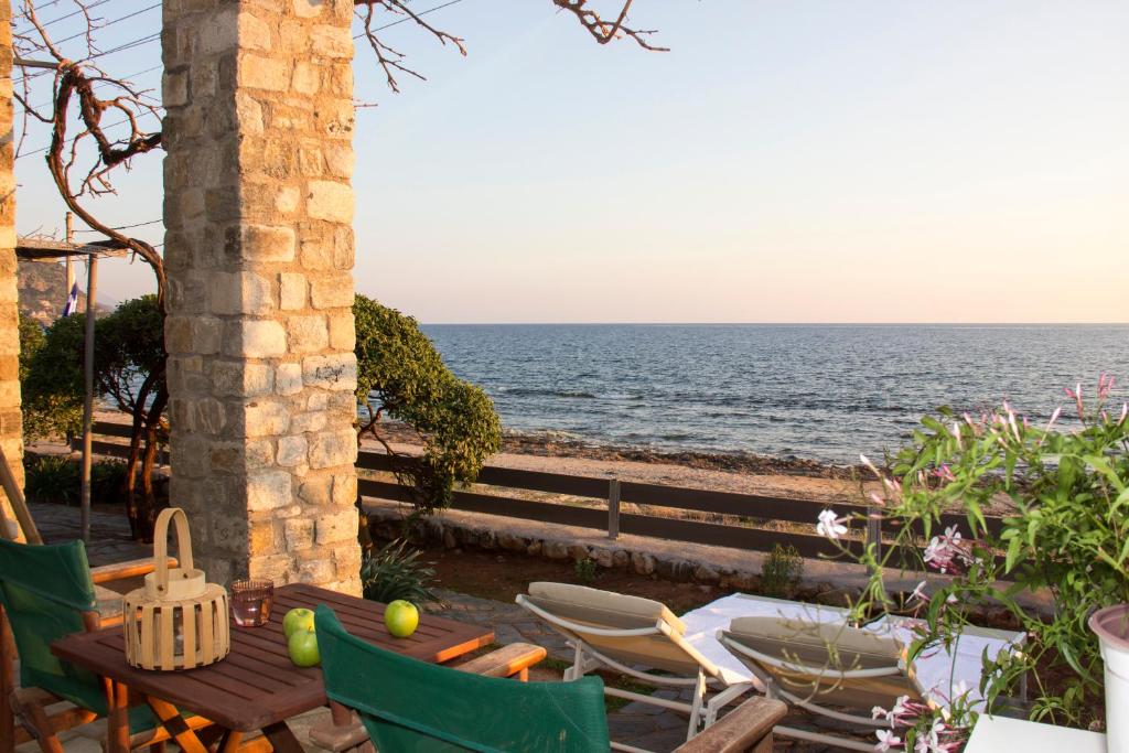 un patio con mesa, sillas y el océano en Bostani Seaside House Mani en Agios Nikolaos